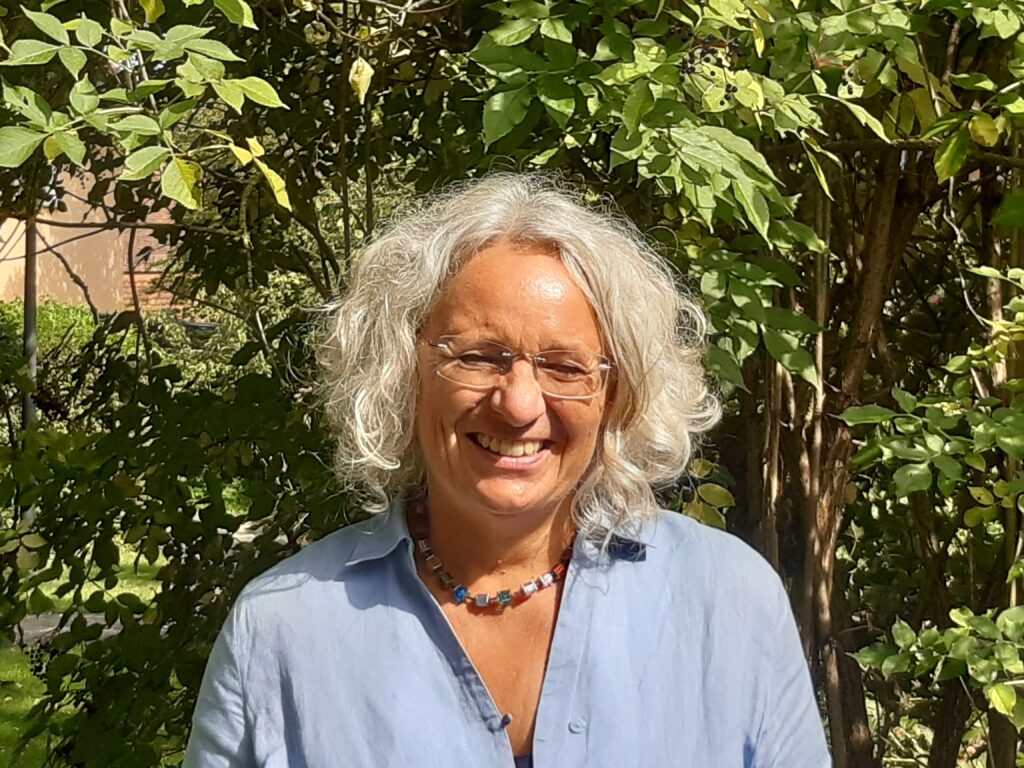 Ältere Person mit grauen Haaren im Garten.