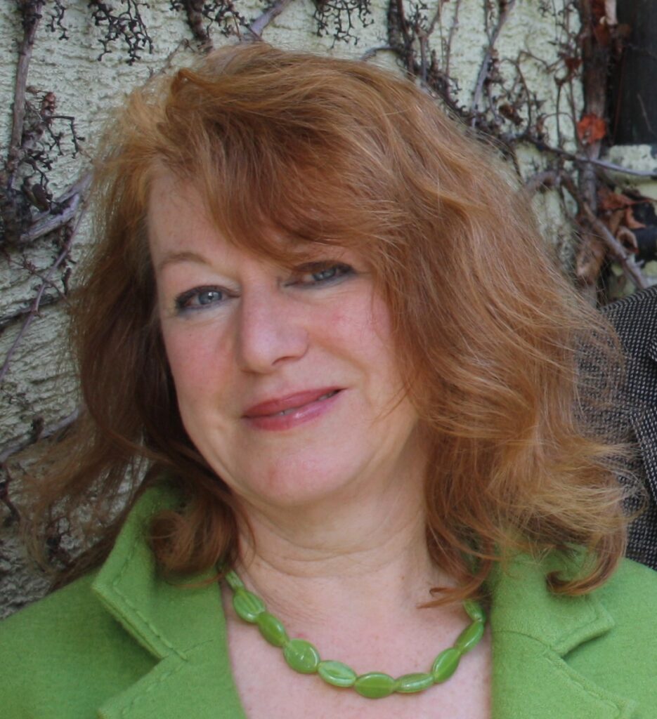 Frau mit lockigem Haar vor Naturhintergrund.