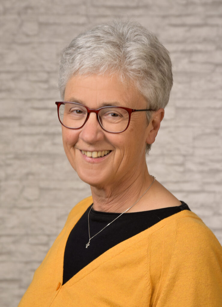 Ältere Frau mit Brille und gelbem Pullover lächelnd