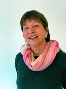 Frau mit rosa Schal lächelt in die Kamera.