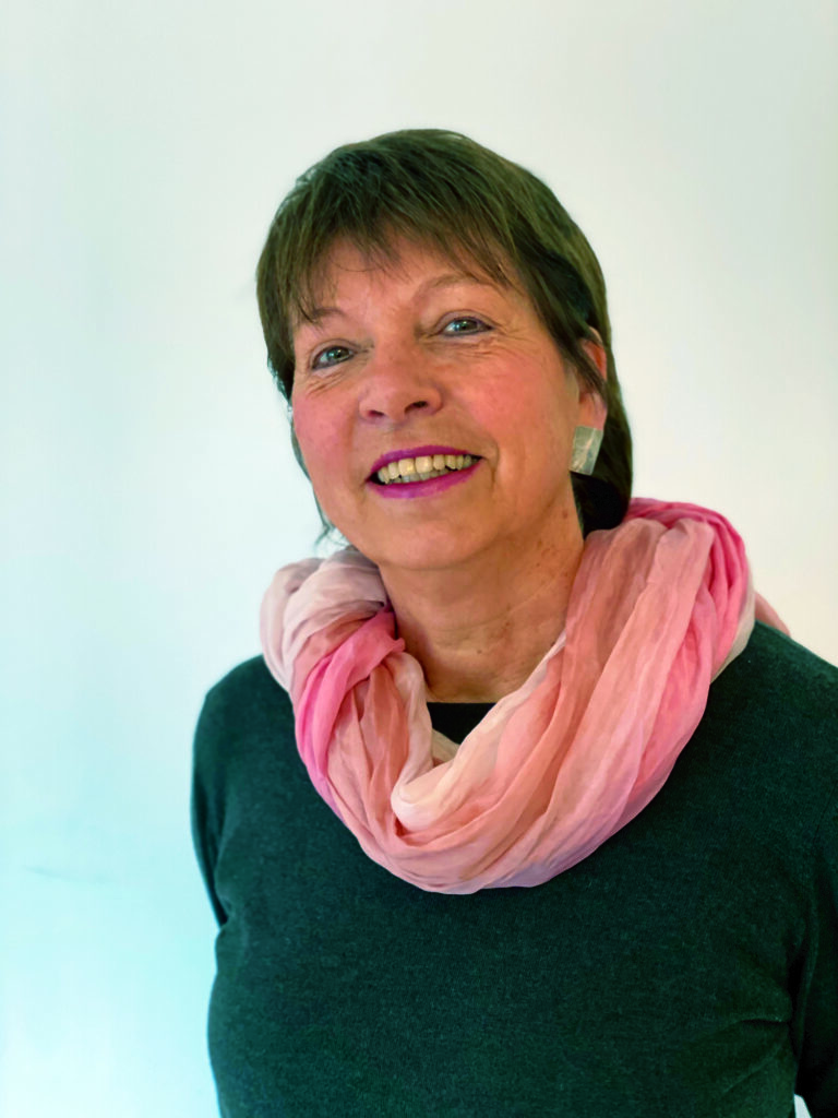 Frau mit rosa Schal lächelt in die Kamera.