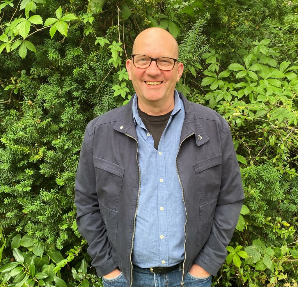 Mann im Freien vor grünen Büschen stehend