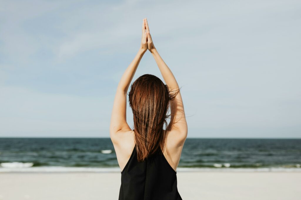 Frau macht Yoga am Strand vor Ozean