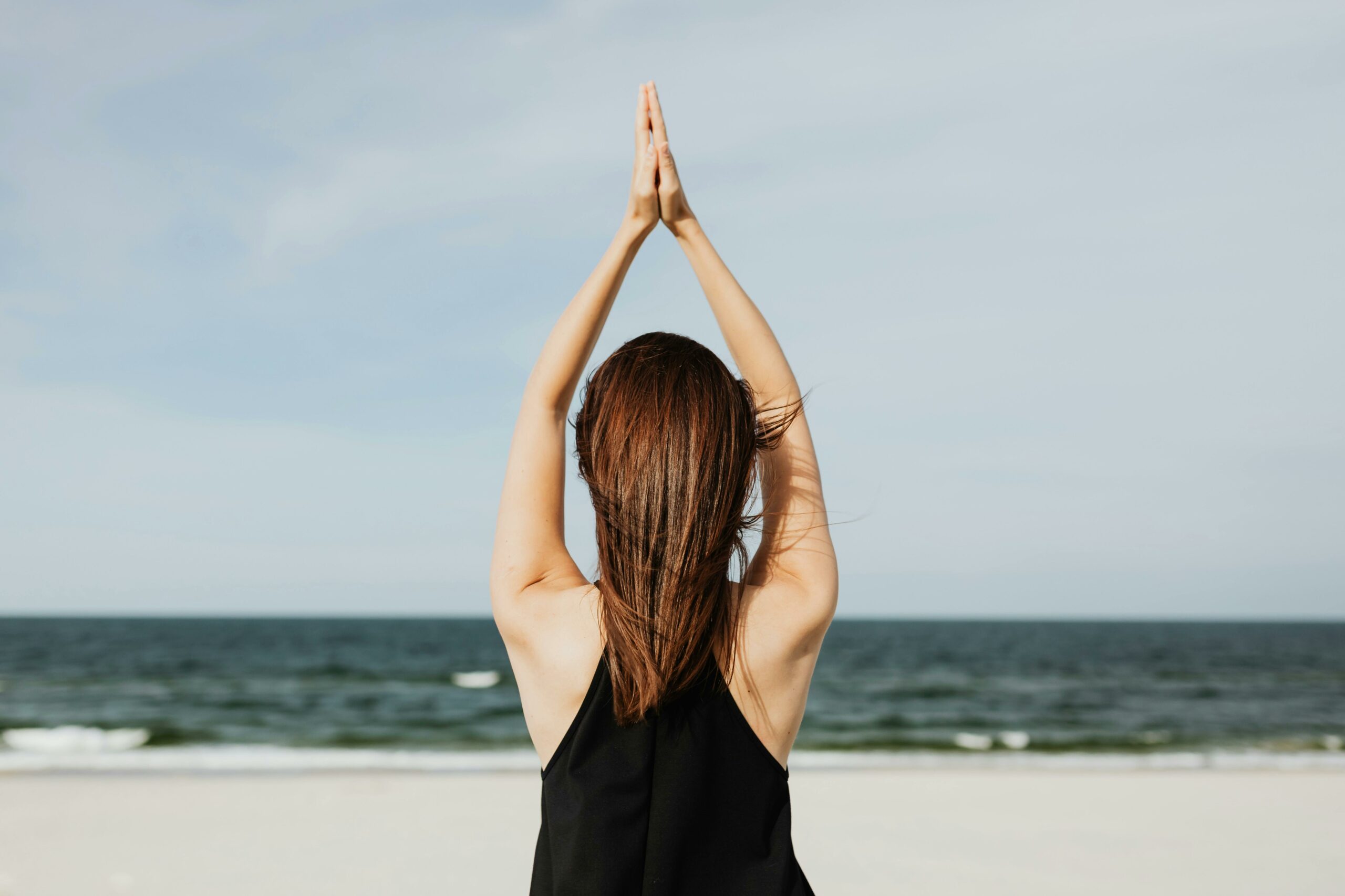 Frau macht Yoga am Strand vor Ozean
