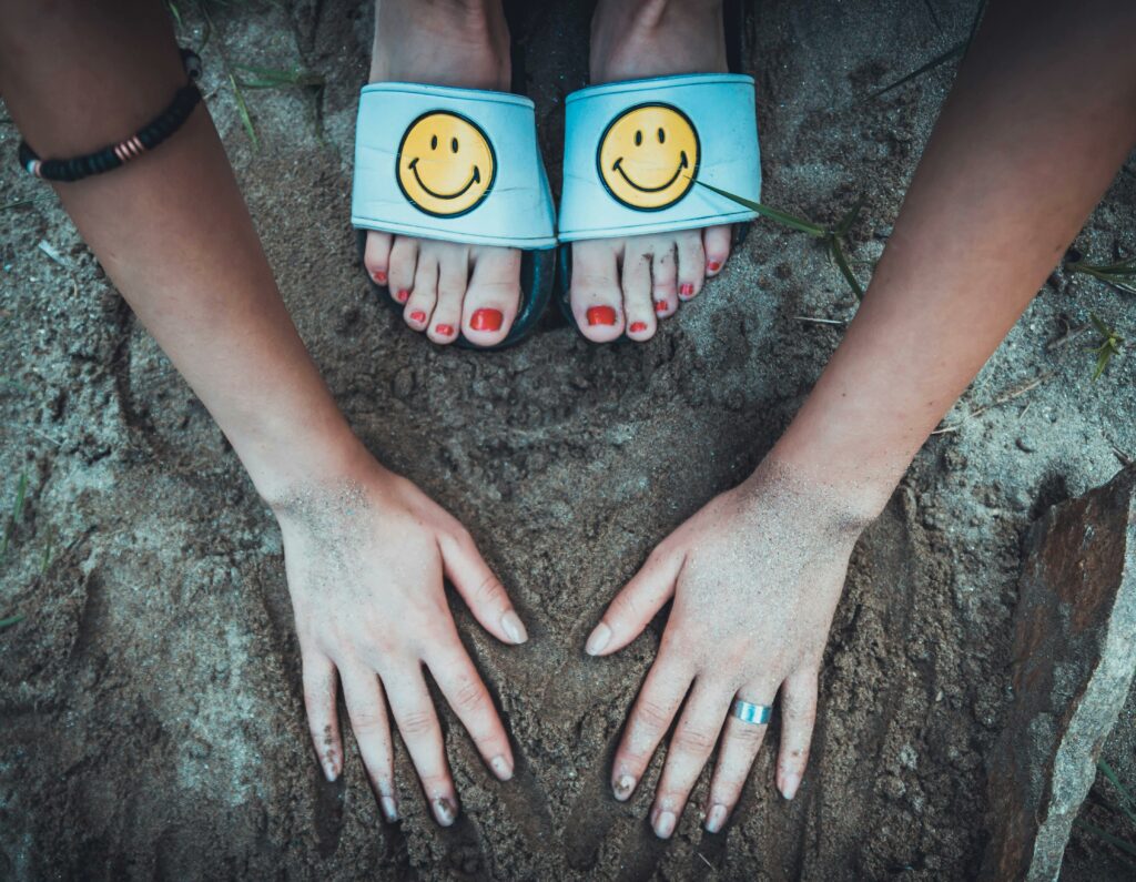 Zwei Hände und Füße im Sand mit Smileys