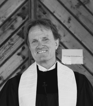 Mann in schwarzer pastoraler Kleidung vor Holzwand