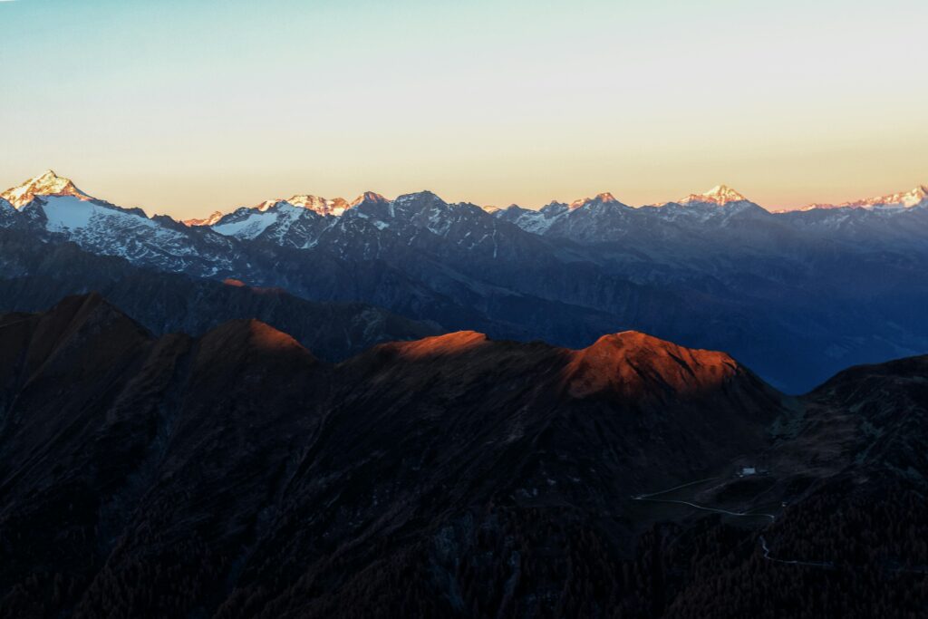 Berglandschaft bei Sonnenuntergang mit verschneiten Gipfeln.