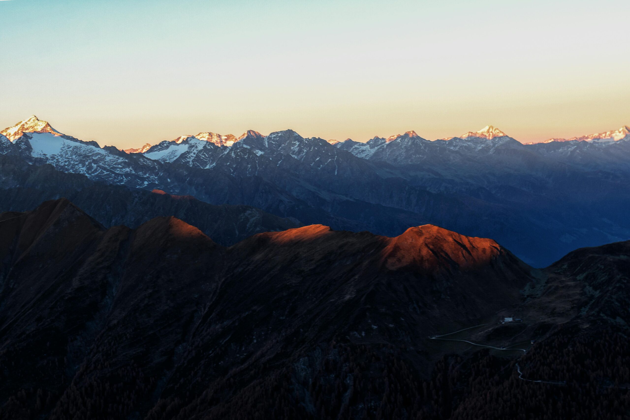 Berglandschaft bei Sonnenuntergang mit verschneiten Gipfeln.