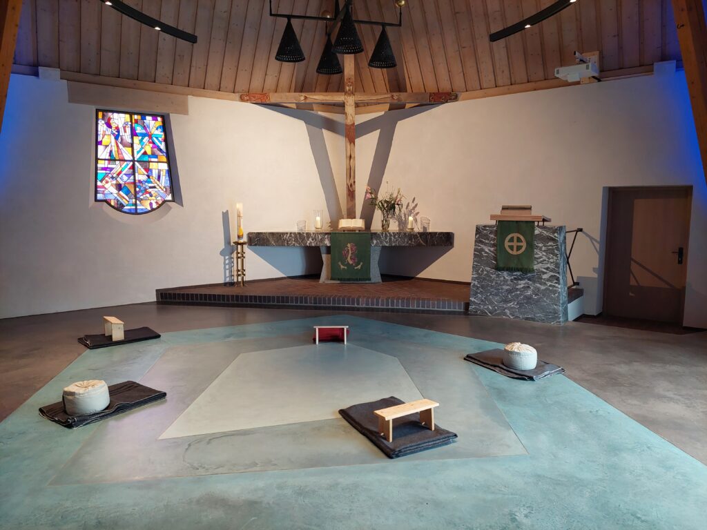 Moderner Kircheninnenraum mit Altar und Bänken.