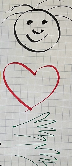 Handgezeichnetes Bild auf Millimeterpapier, das ein lächelndes Gesicht, ein rotes Herz und darunter grüne Schnörkel zeigt, die an Gras oder Linien erinnern.